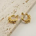 Elegante 18K vergoldete Edelstahl-Creolen in gedrehter Form auf Stein-Hintergrund - Gold