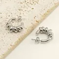 Boucles d'oreilles créoles torsadées argentées sur fond de pierre travertin - Acier