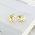 Detail van gouden kersenbloesem oorknopje met wit kristal en platte schroefsluiting - Goudkleurige Holle Vijfbladige Bloem Met Zirkonia Knopstijl