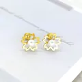 Macro-opname van gouden kersenbloesem oorbellen met witte parels en schroefsluiting - Goudkleurige Holle Vijfbladige Bloem Met Parel Knopstijl