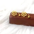 Macro-opname van gouden kersenbloesem oorknopjes met een U-vormige schroefsluiting - Goudkleurige Holle Kersenbloem Met Kraal U-Vorm Stijl