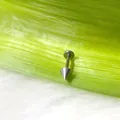 Vista macro di piercing labret a punta in titanio argento su una foglia verde - Punta grande