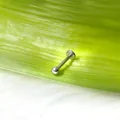 Primo piano di un labret in titanio con sfera su una foglia verde naturale - Sfera