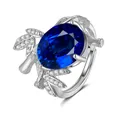 Macro shot of silver ring featuring oval blue gemstone and diamond-set leaf texture - Adjustable Open / Sapphire