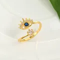 Macro detail of golden evil eye ring with blue and white crystals on ceramic tray - Adjustable Open / Gold
