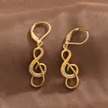 Detailed close-up of gold music note earrings with micro-inlaid cubic zirconia stones - Gold