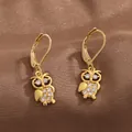 Detail of gold owl leverback earrings featuring micro-pave cubic zirconia on silk texture - Gold