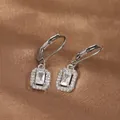 Detailed view of silver leverback earrings with rectangular cubic zirconia on satin background - White Gold