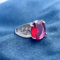 Close-up of pigeon blood red oval gemstone ring with silver setting on blue fabric - Adjustable Open / Red Gemstone Style (QHJ008)