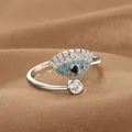 Macro shot of silver evil eye open ring featuring blue zircon inlay on brown fabric - Pave Evil Eye Style (Q-J073) / White Gold