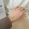 Nahaufnahme eines polierten Herzanhänger-Armbands aus Gold im minimalistischen Stil - Herz Armband / Gold