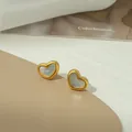 Macro detail of heart-shaped earrings with gold edges and iridescent mother of pearl inlay - White Shell Heart Stud (XKE0217)