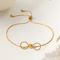 Detail view of gold bow charm on a snake bone chain with an adjustable pull clasp - Bow Bracelet / Gold