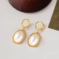 Elegant gold oval pearl drop earrings with matte finish and secure hoop closure - Oval Pearl Earrings / Gold