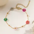 Makroaufnahme eines goldenen Edelstahl-Armbands mit fünf bunten perlenbesetzten Blumen - Bunte Perlenblume (XKB0153)