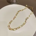 Detailansicht einer goldenen Büroklammer-Halskette auf einem weißen Keramiktablett - Halskette / Gold
