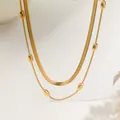 Detail einer zweilagigen goldenen Halskette mit flacher Schlangenkette und Perlengliedern - Doppellagige Halskette-Gold (XKN1156)