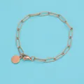 Dettaglio del bracciale a maglie in oro rosa con ciondolo rotondo su sfondo azzurro - 15cm / Oro rosa