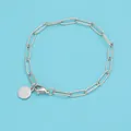 Dettaglio del bracciale a catena argentato con ciondolo circolare e chiusura a moschettone - 15cm / Colore acciaio
