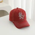 Detailopname van rode katoenen baseballpet met grijze dinosaurus borduurwerk op wit vlak - Verstelbaar / Rood