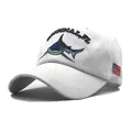 Detail of shark embroidery and American flag patch on white cotton baseball cap - White
