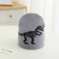 Dettaglio di berretto grigio in maglia con motivo a scheletro di dinosauro nero ricamato - Taglia unica / Grigio