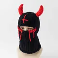 Detail einer gestrickten Sturmhaube mit roten Teufelshörnern und Kreuzmuster am Kopf - Schwarz Rotes Kreuz Teufelshörner