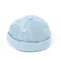Dettaglio del berretto docker in denim celeste con fori usurati e trama retrò sfrangiata - Regolabile / Azzurro