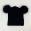 Close-up of black knitted beanie featuring two large fluffy faux fur pom-poms on top - One Size / Black