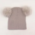 Detailed view of kids ribbed knit hat featuring two large fluffy faux fur pompoms - One Size / Beige
