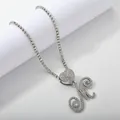 Detailed view of silver tennis chain with iced-out heart and cursive letter M pendant - Silver Set M