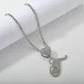 Detail of silver tennis chain featuring a iced-out heart and cursive letter T pendant - Silver Set T