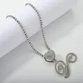Close-up of sparkling silver tennis chain with heart pendant and iced out script initial - Silver Set V