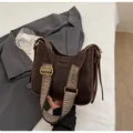 Detalle de bolso de cuero marrón con correa ancha de tejido geométrico y hebilla dorada - café