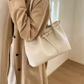 Detalle de un bolso tote de cuero granulado blanco crema con hebilla metálica y asa - Estilo básico / Blanco
