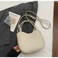 Detailed macro view of cream white crescent handbag with pebbled texture and silver buckles - Soy White