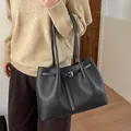 Detalle de bolso tote negro en cuero granulado con hebilla plateada llevado por una modelo - Estilo básico / Negro