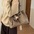 Primer plano del bolso tote de cuero marrón oliva con colgantes de perro y béisbol - Con Colgante / Gris