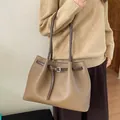 Detalle macro del bolso tote taupe con textura de grano lichi y correa de hebilla - Estilo básico / Gris