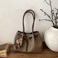 Makrodetail der braunen Tragetasche aus genarbtem Leder mit dekorativem Kordelzug - Grau Mit Anhänger