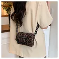 Detail of leopard print crossbody bag with matte black chain strap and front zipper - Brown