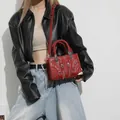 Chic red motorcycle bag with metallic studs and woven handles in crossbody style - Red