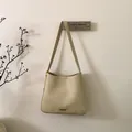 Dettaglio della borsa tote in pelle crema con trama stropicciata vintage e logo in metallo - Bianco Sporco