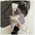 Detail van lichtpaarse tas met gevlochten handvat en parel-kant strik hanger sieraad - Paars