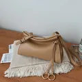 Detail der kamelfarbenen Ledertasche mit oberen Falten und goldenen Metallring-Akzenten - Khaki