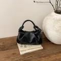 Detailansicht der schwarzen Falten-Cloud-Bag mit geknotetem Griff auf Holzfläche - Schwarz