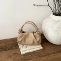 Detailansicht der beigen Falten-Handtasche aus weichem mattem Leder auf einem Holzschreibtisch - Khaki