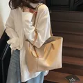 Elegante borsa tote crema con cinturini marroni indossata da una modella per un look chic - Cachi