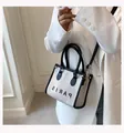 Gedetailleerd overzicht van canvas draagtas met leren bies en Paris-print op een witte blazer - Klein / Zwart
