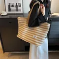 Large khaki and white striped canvas tote bag with fashion label shown in a lifestyle setting - Khaki